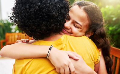 Two teenagers hug one another.