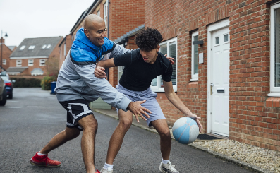 An man playing basketball with a teenage boy.