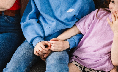 Two young siblings hold eachothers hands.