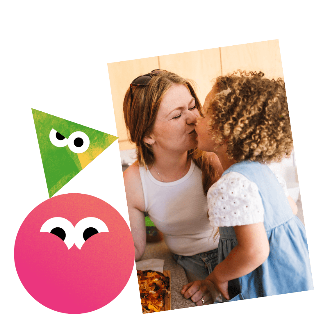 A mother kissing her young daughter while preparing a meal.