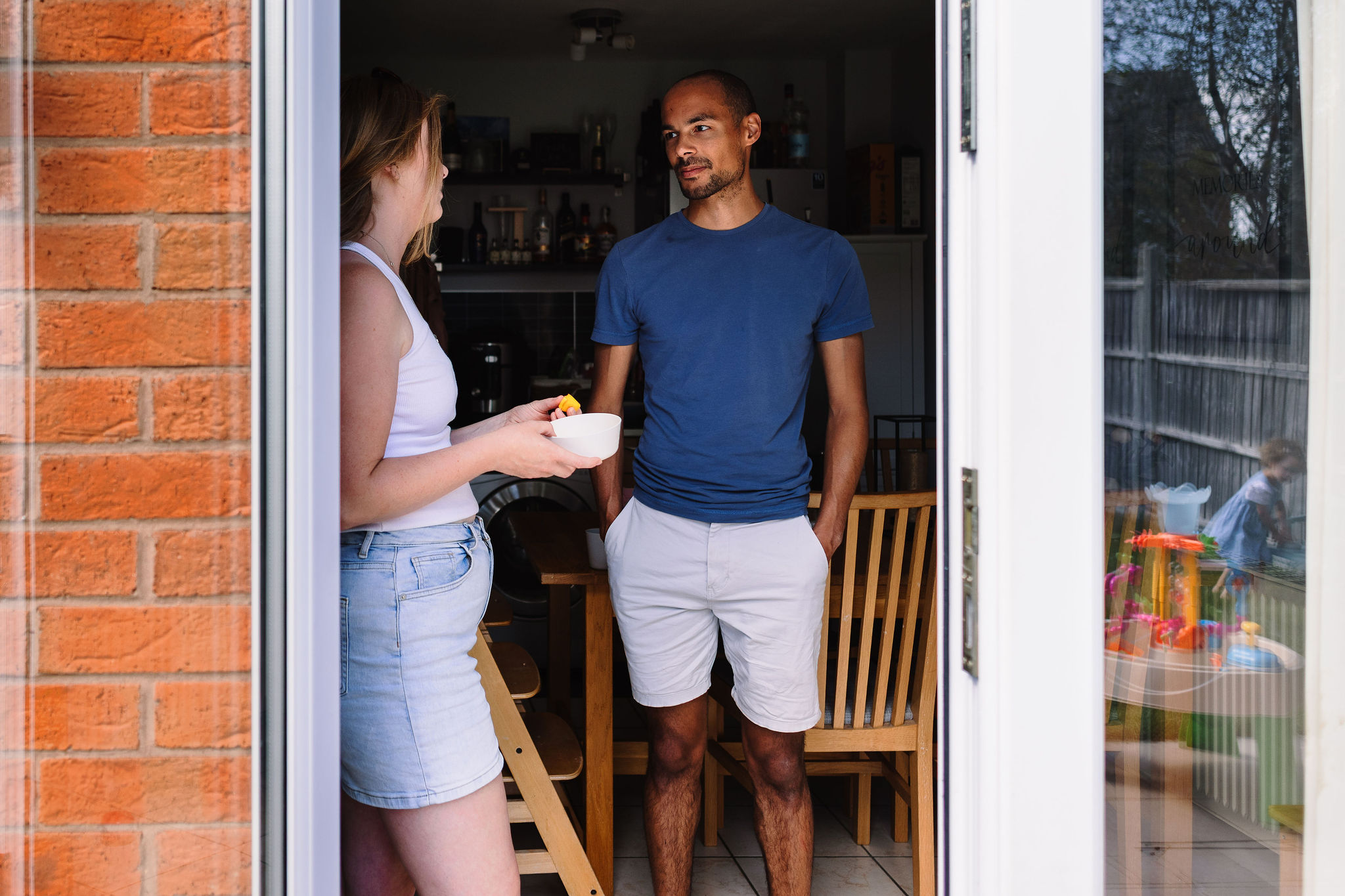 A couple standing in their kitchen having a conversation.
