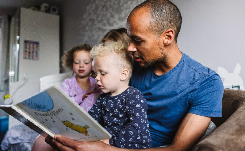 A father reading his son and daughter a bedtime story.