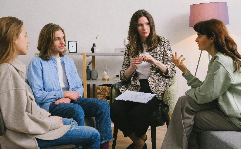 Four people sit facing each other during a group meeting.