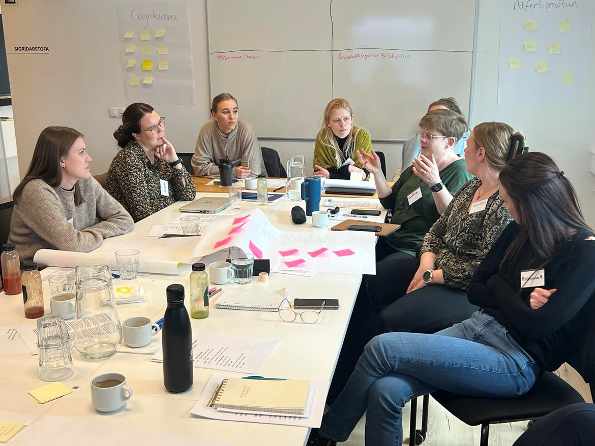 A group of practitioners are sitting around a table having a discussion.