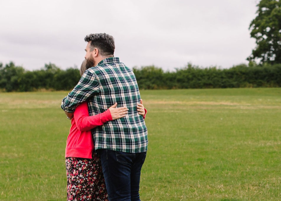 Two adults hugging outside.