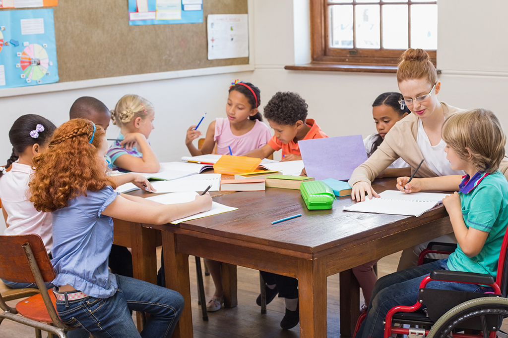 A teacher helping pupils learn to write in a classroom