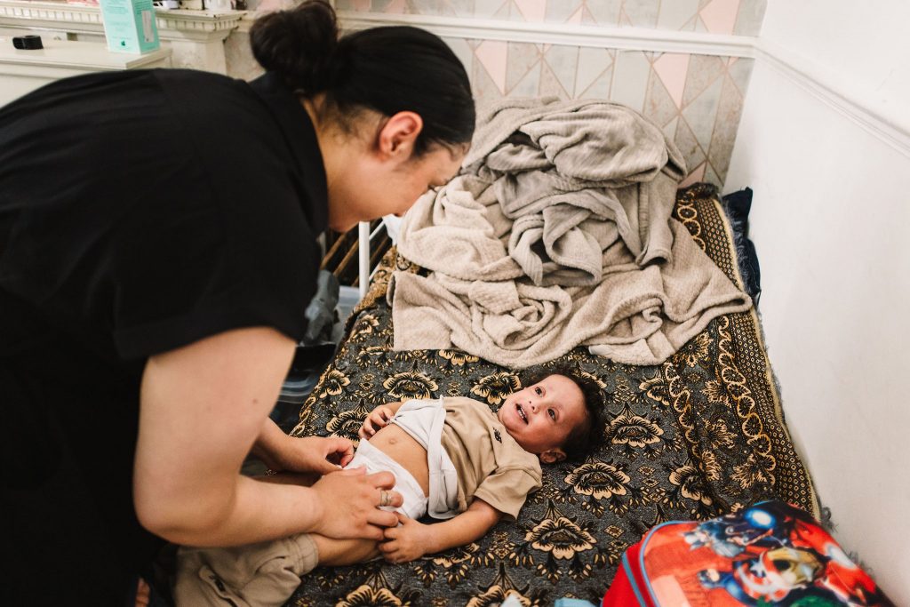Parent changing child's nappy on a bed.