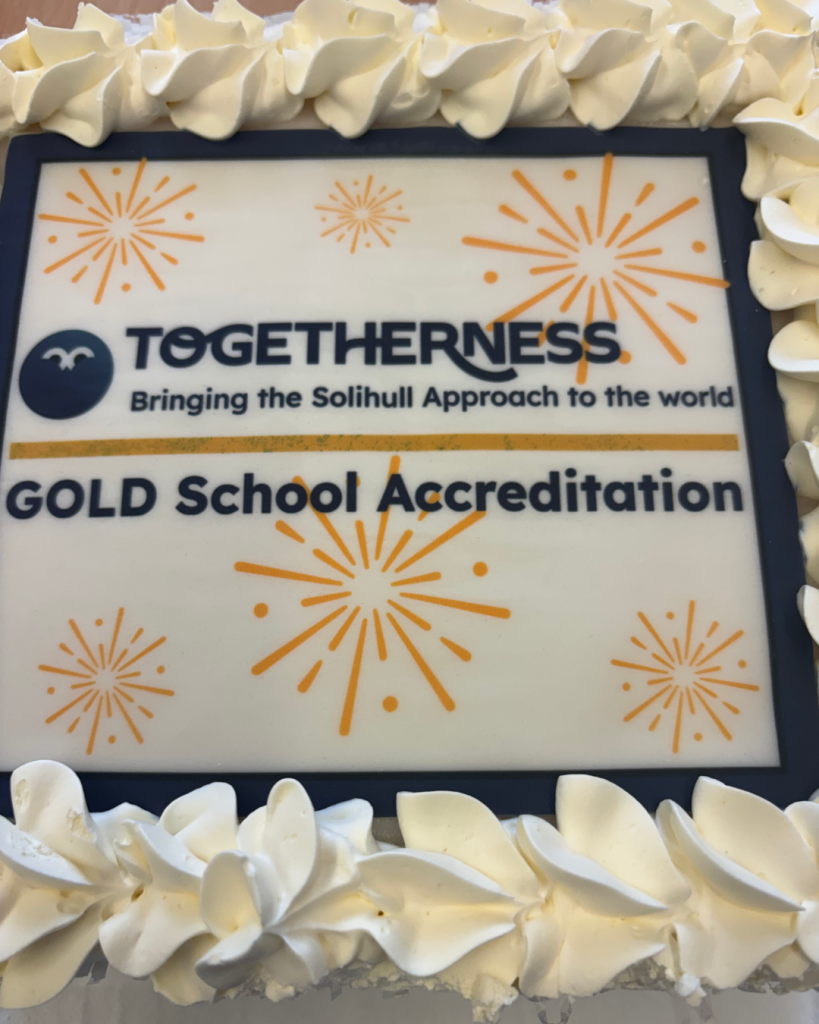 Cake with the Togetherness school accreditation badge printed on it. Badge reads 'Togetherness. Bringing the Solihull Approach to the world. GOLD School Accreditation.'