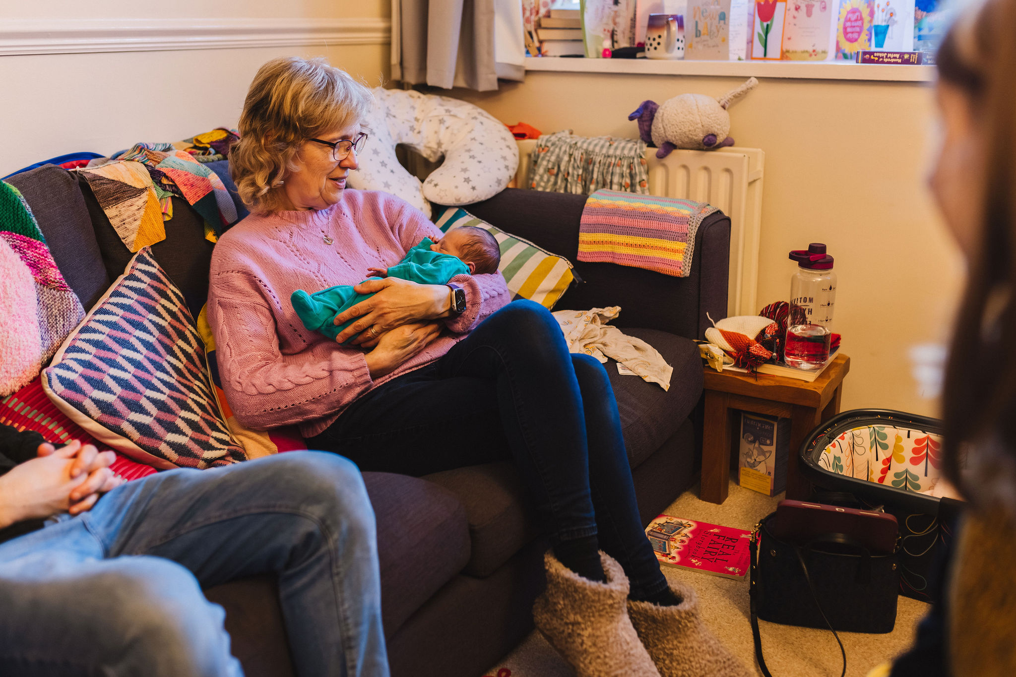 Grandma sat on sofa holding newborn baby