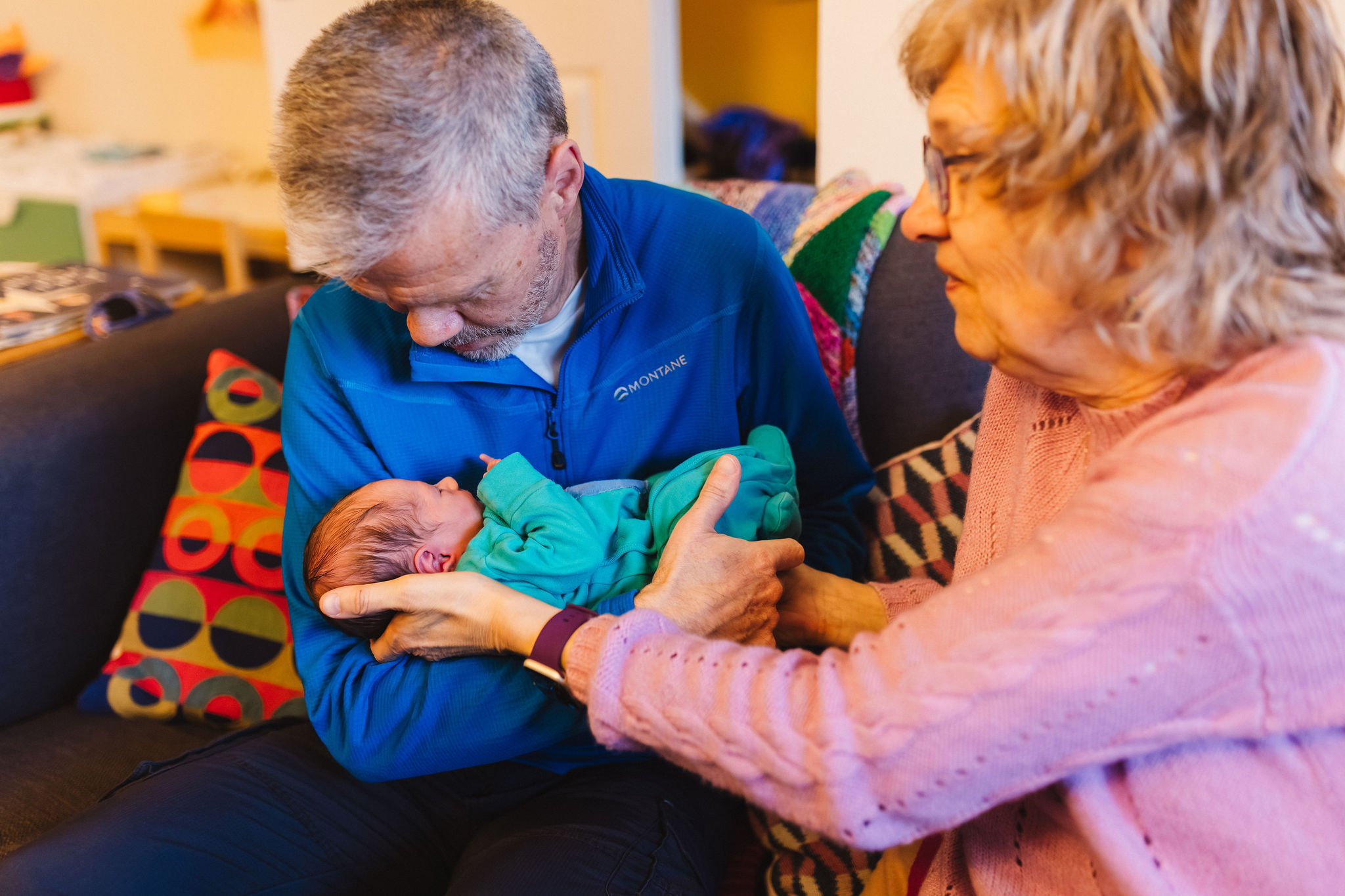 Grandma helping Grandad hold newborn baby